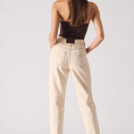 Woman wearing a strapless top and beige pants on a white background