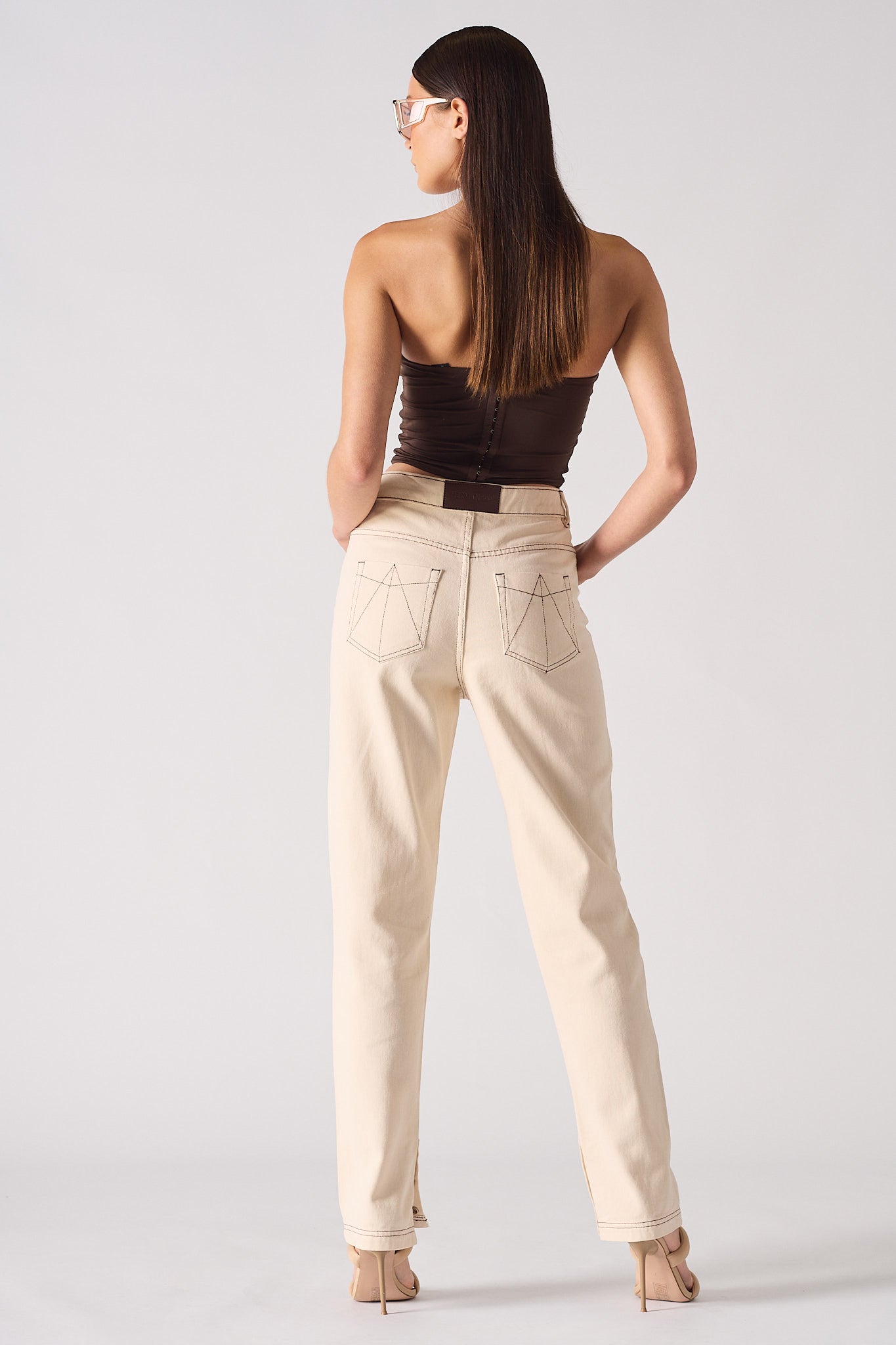Woman wearing a strapless top and beige pants on a white background