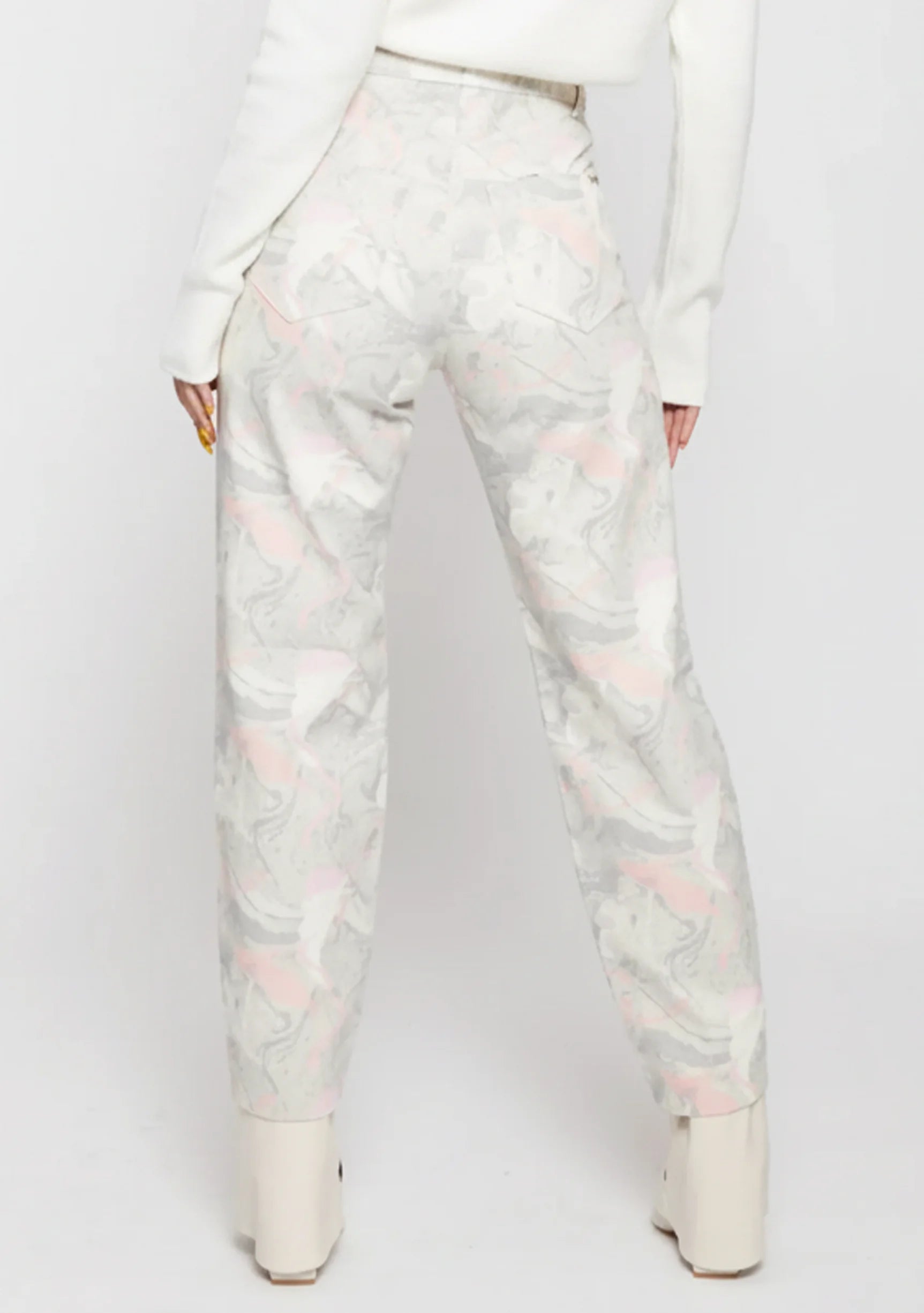 Full back view of a model wearing abstract swirl pattern high-rise jeans with classic back patch pockets.