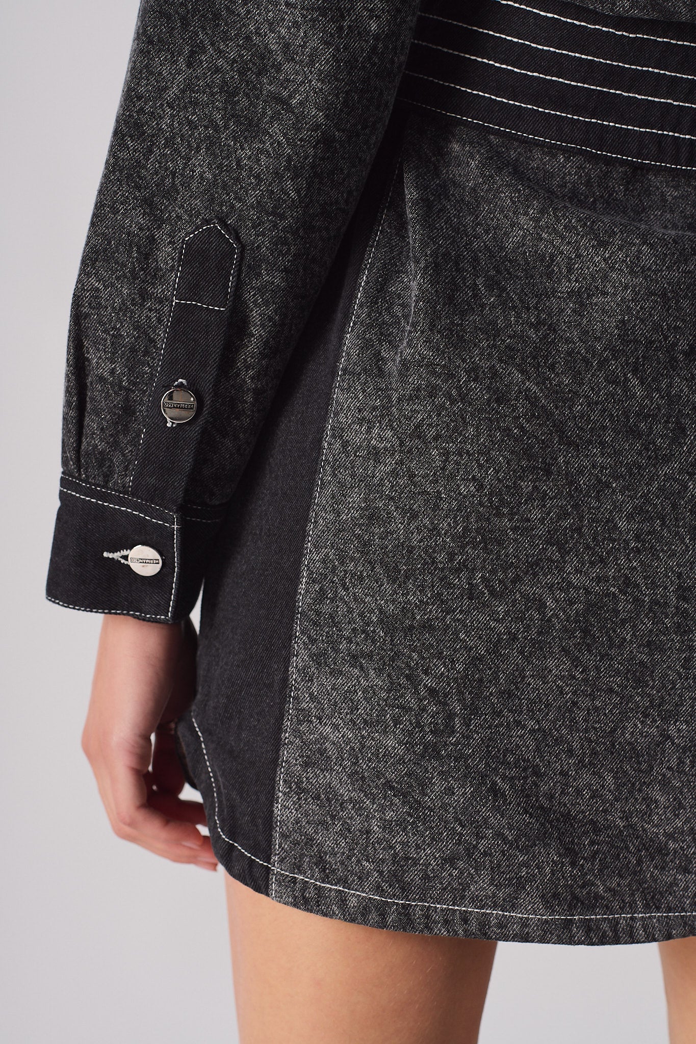 Close-up showing the sleeve cuff and dark side panel on the acid wash denim dress