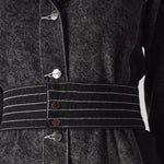 Detailed close-up of the white contrast stitching on the belt of the acid wash dress