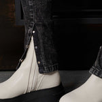 Detailed view of the split hem with poppers on the acid wash jeans over boots