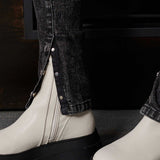 Detailed view of the split hem with poppers on the acid wash jeans over boots
