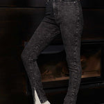 Side view of a model wearing acid wash skinny jeans with the popper hem open