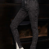 Side view of a model wearing acid wash skinny jeans with the popper hem open