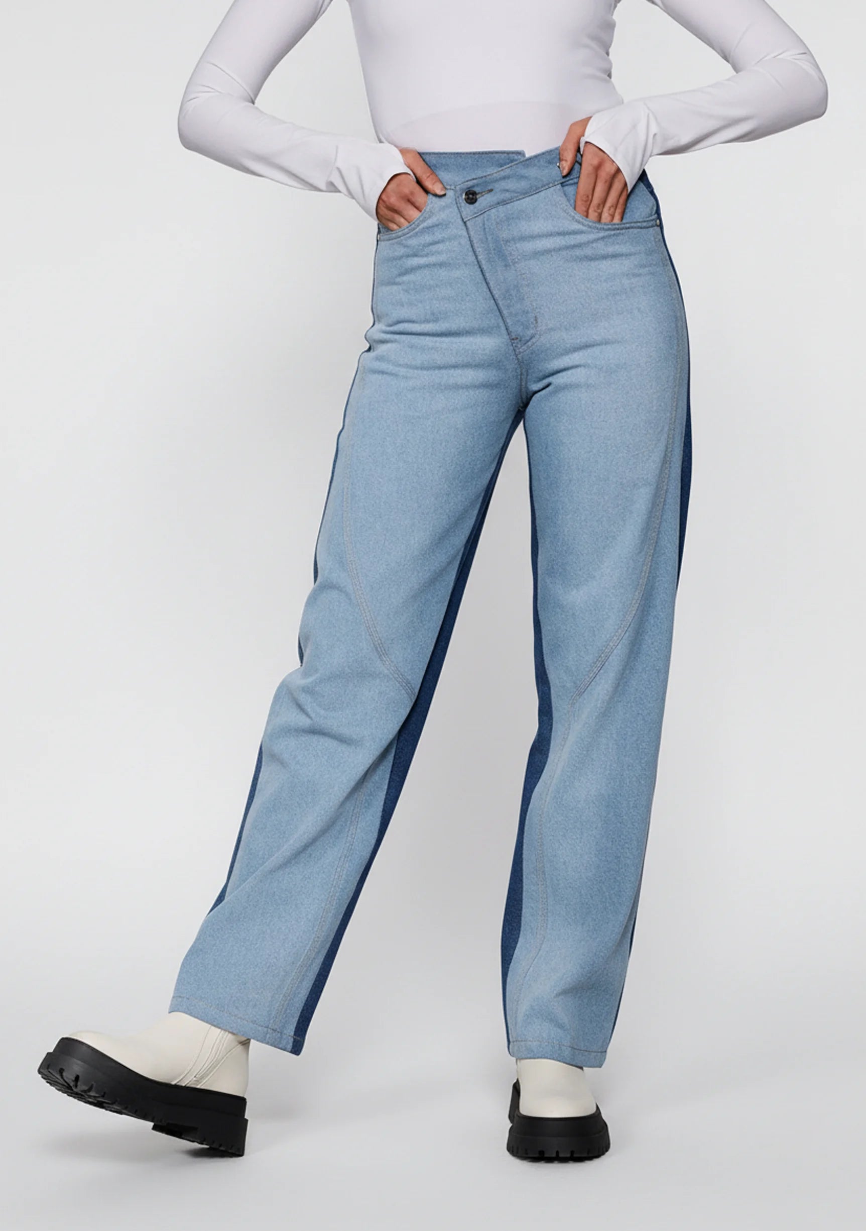 Front view of women's two-tone wide leg jeans featuring an asymmetrical crossover waistband