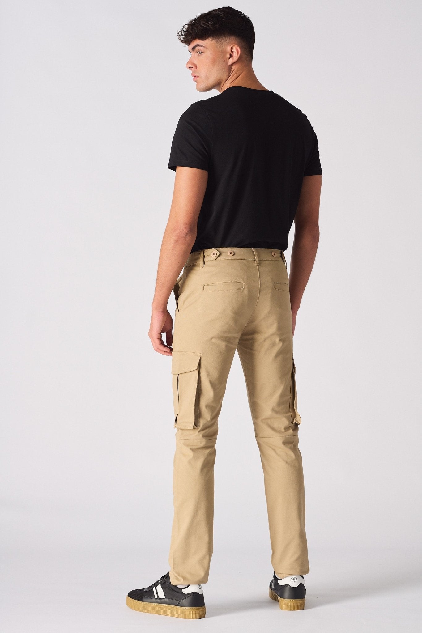 Rear view of a man wearing beige cotton cargo pants with visible back pockets.