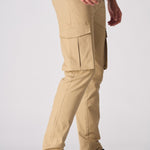 Side profile of a model wearing beige cotton cargo pants showing the functional side pockets.