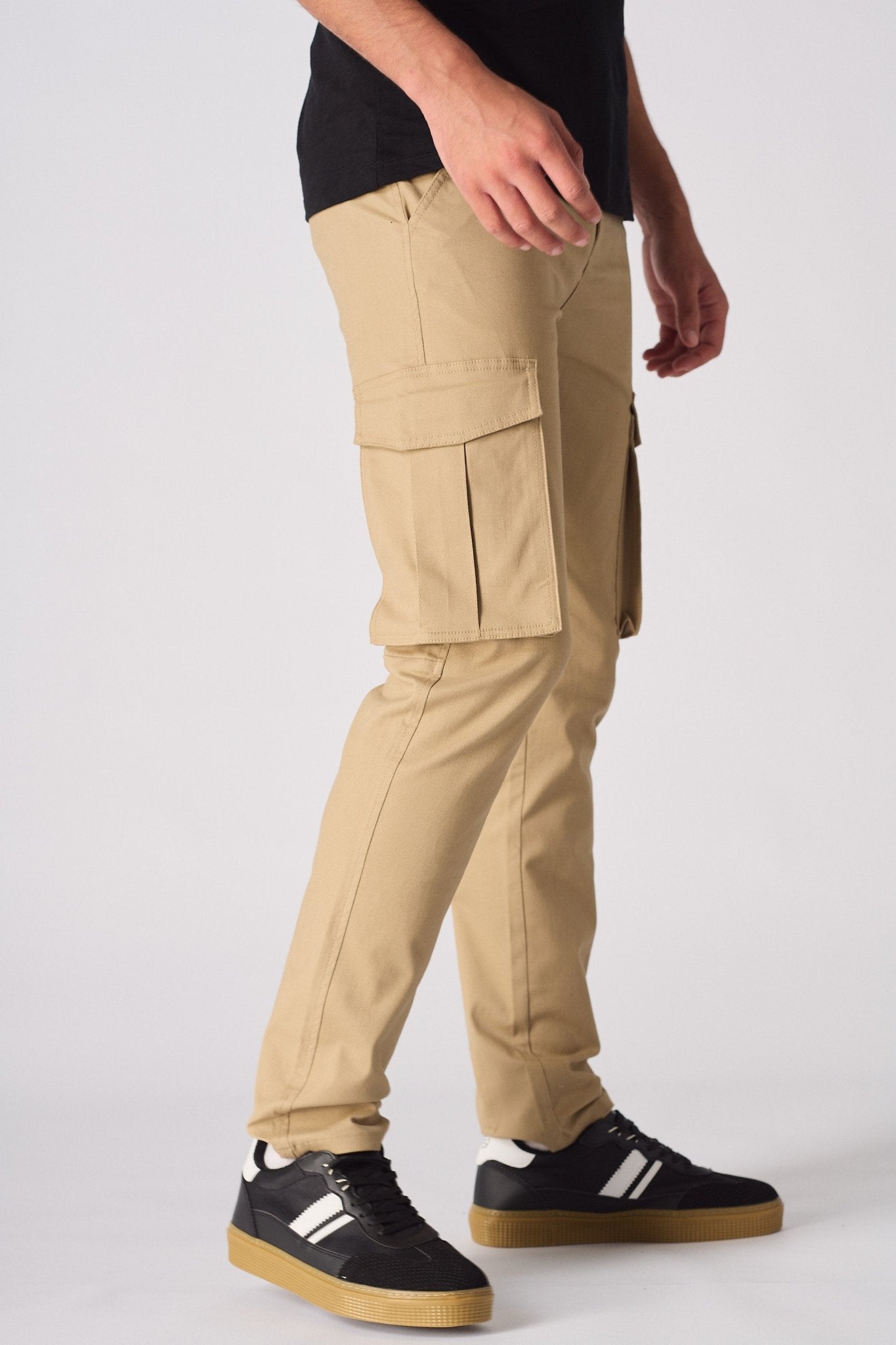 Side profile of a model wearing beige cotton cargo pants showing the functional side pockets.