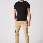 A man standing in beige cotton cargo pants showing the modern utility design.