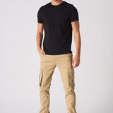 A man standing in beige cotton cargo pants showing the modern utility design.