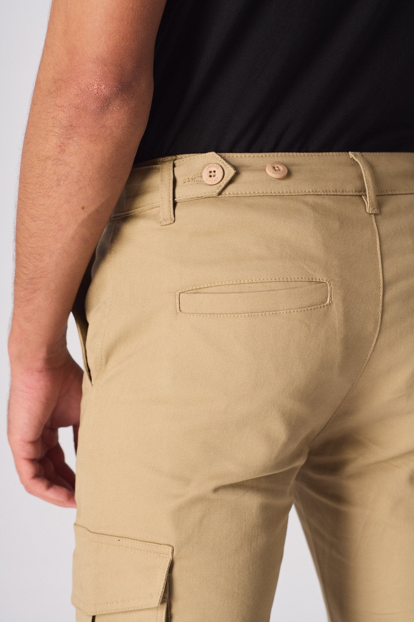 Close up of the back of the beige cotton cargo pants showing the adjustable waist strap.