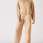 Full front view of a woman wearing a beige hoodie and matching wide leg joggers