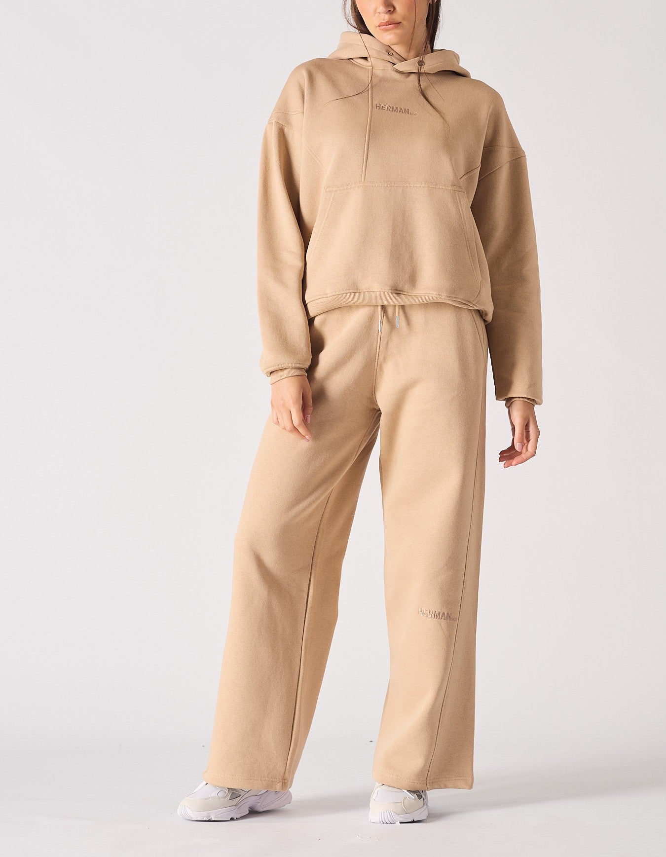 Full front view of a woman wearing a beige hoodie and matching wide leg joggers