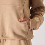 Detailed view of the hand pocket and soft fabric on a beige hoodie for women