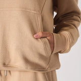 Detailed view of the hand pocket and soft fabric on a beige hoodie for women