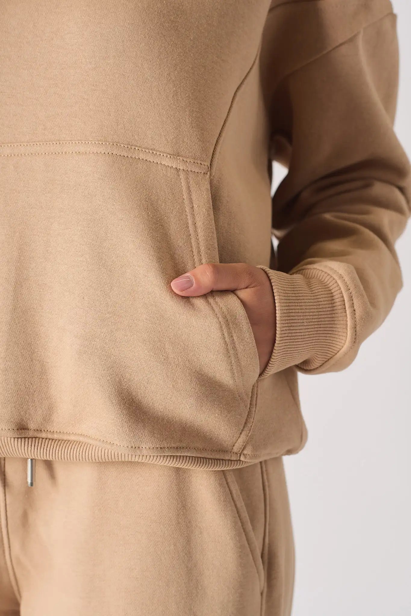 Detailed view of the hand pocket and soft fabric on a beige hoodie for women
