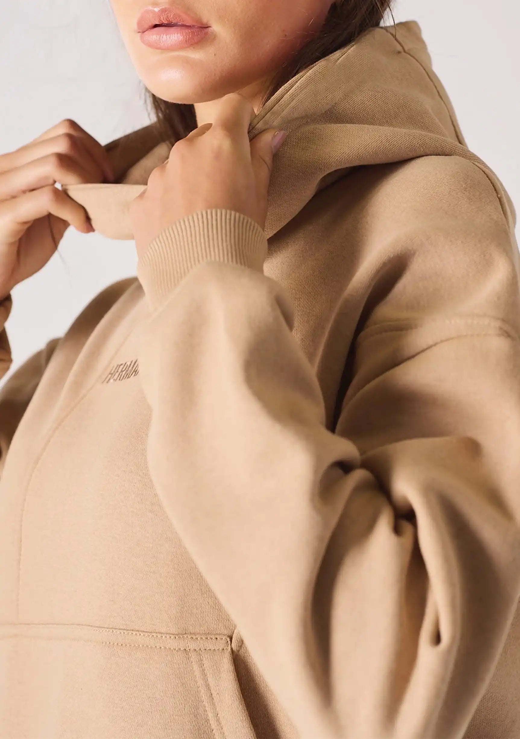 Side view of the popper neck and shoulder of a beige hoodie womens style