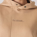 Close up of the tonal embroidered insignia on a beige hoodie for women