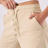 Close up showing the drawstring waist and pocket on beige straight leg cargo pants.