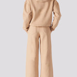 Rear view of a model wearing beige wide leg joggers and a matching hoodie