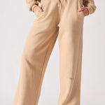 A front view of a woman wearing beige wide leg joggers with hands in her pockets