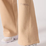 Detailed view of the discreet tonal logo on the beige wide leg joggers