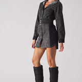 Side angle of a model wearing the black acid wash denim dress with high boots