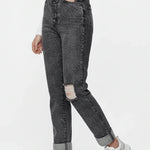 Person wearing black acid-wash jeans with a white top and white sneakers on a white background