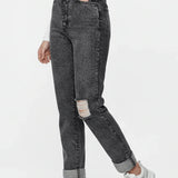 Person wearing black acid-wash jeans with a white top and white sneakers on a white background