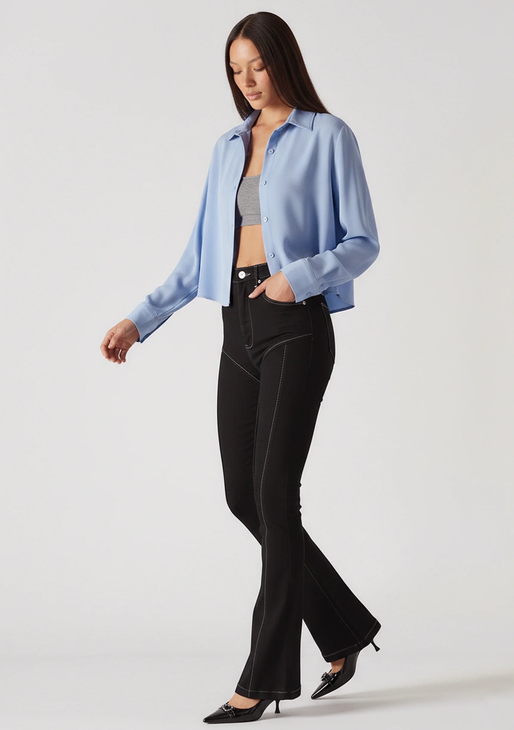 Model walking wearing black bootcut jeans, highlighting the unique front yoke and contrast stitching