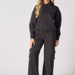 Detailed view of the three dimensional cargo pocket on black wide leg trousers