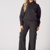 Detailed view of the three dimensional cargo pocket on black wide leg trousers