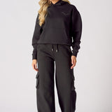 Full length front view of a model styling black wide leg cargo joggers and a hoodie