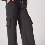 Close up shot of the cargo pocket and drawstring waist on black joggers