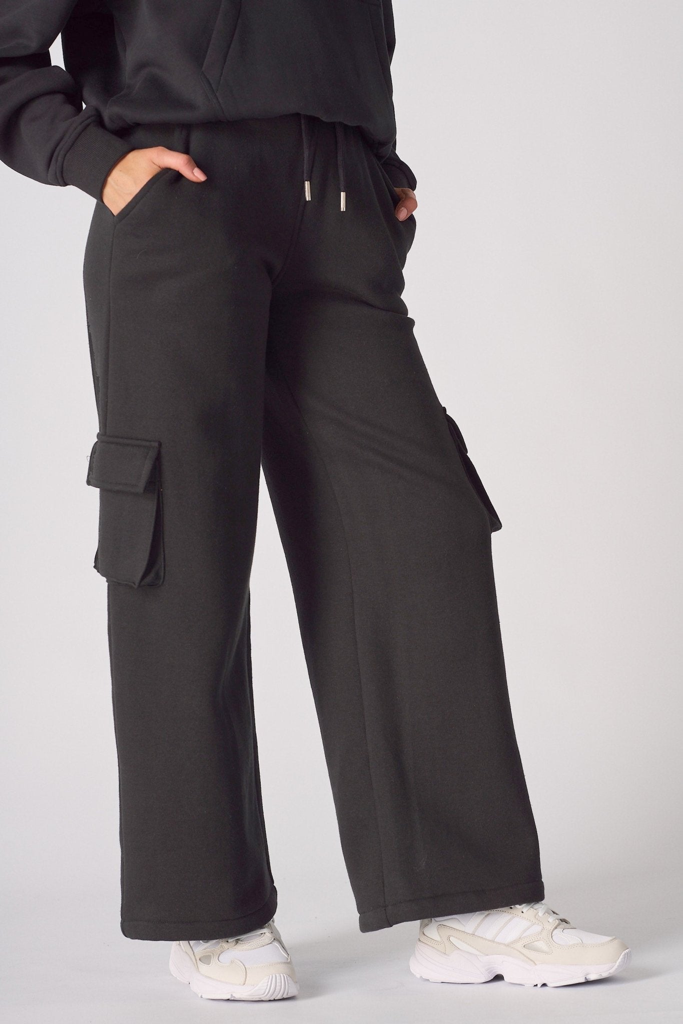 Close up shot of the cargo pocket and drawstring waist on black joggers