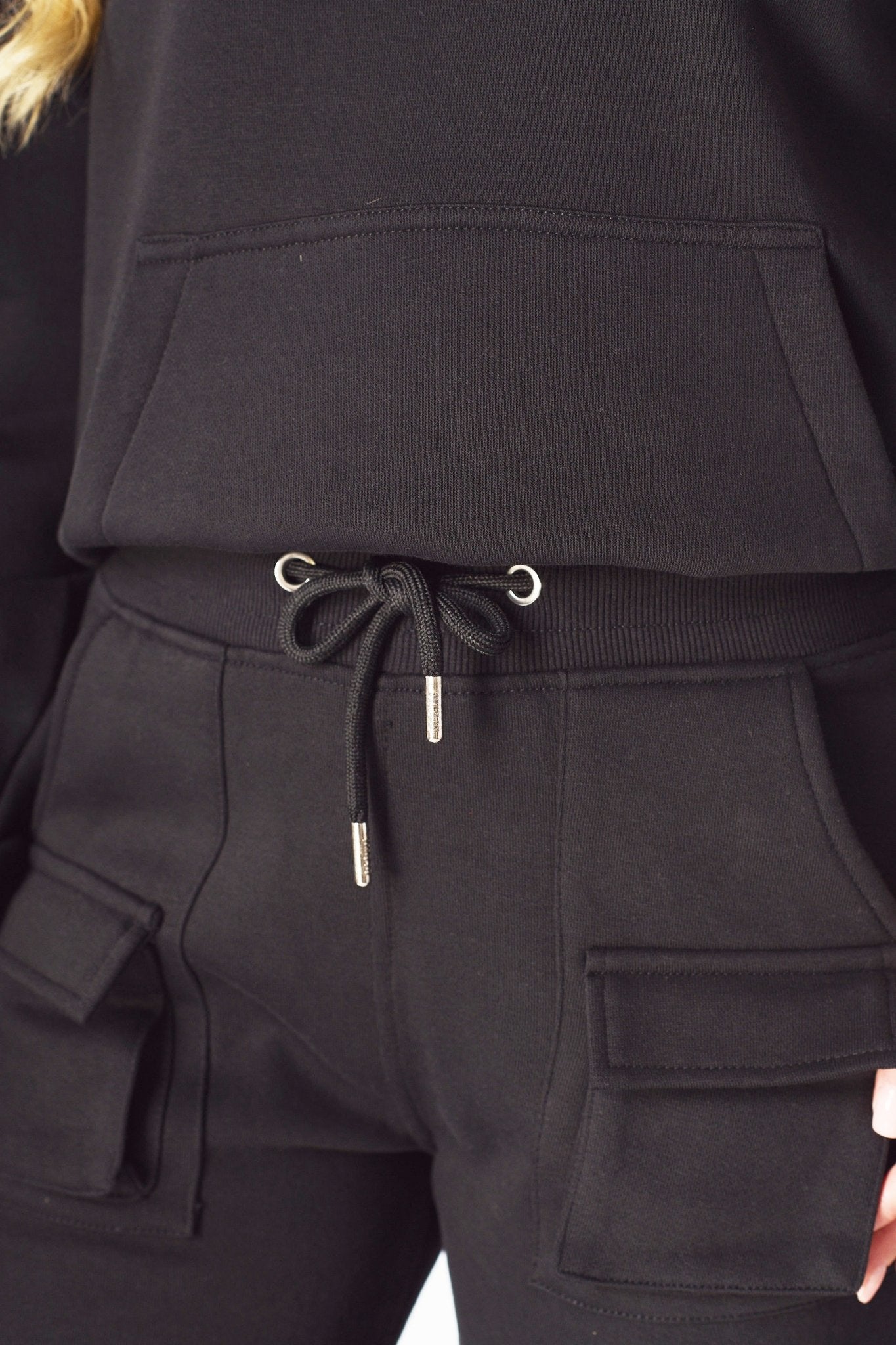 Close up showing the adjustable ankle toggles on the black cargo trousers.
