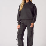 Full body shot of a model wearing black cargo trousers womens straight leg and a matching hoodie.