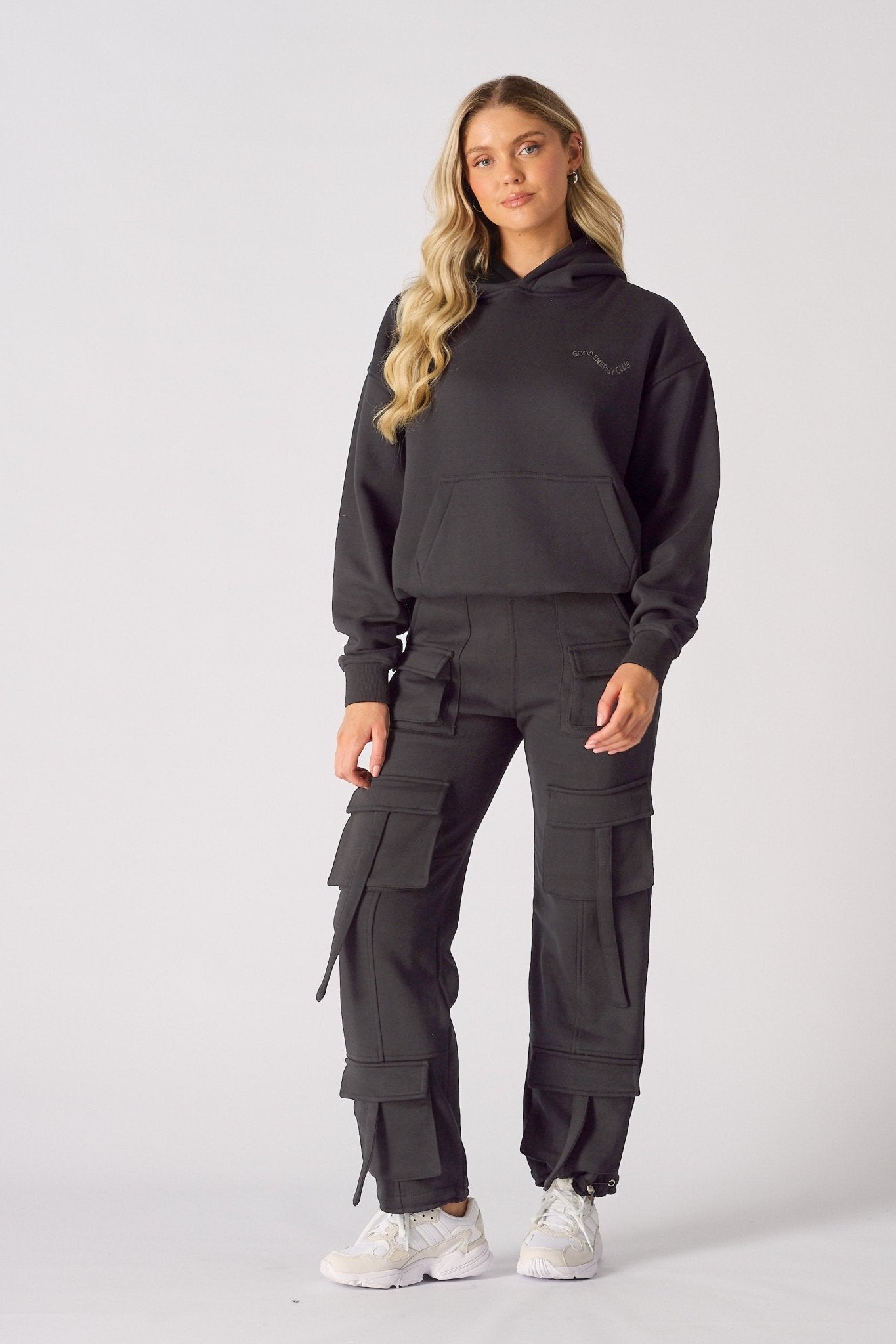 Full body shot of a model wearing black cargo trousers womens straight leg and a matching hoodie.