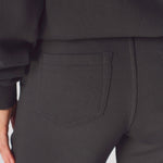 Detailed view of a single side pocket on the black cargo trousers.