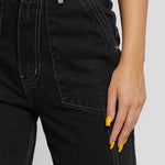 Macro shot of black denim waist showing fabric texture, button closure, and white stitching.