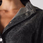 Close-up view of the collar and button details on the black denim dress