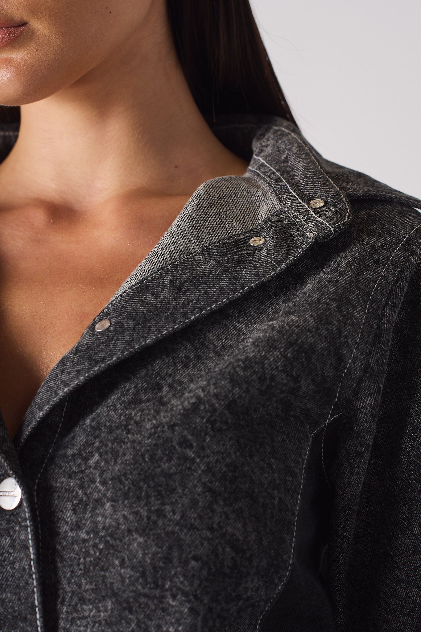 Close-up view of the collar and button details on the black denim dress