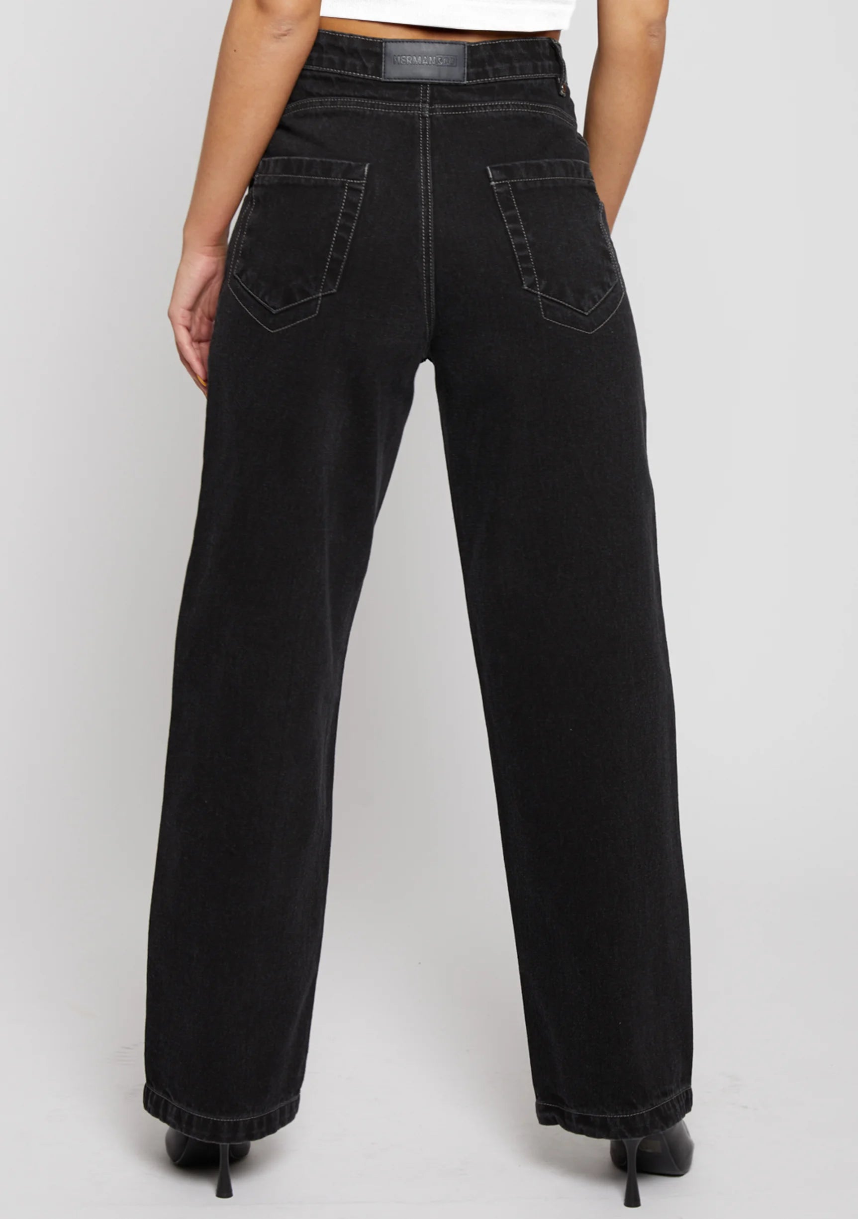 Close-up rear view of black denim jeans highlighting back pockets and yoke construction.