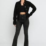 Women wearing black denim trucker jacket with hand on hip - button front cotton jacket styled with high waist flare jeans