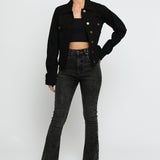 Women wearing black denim trucker jacket with hand on hip - button front cotton jacket styled with high waist flare jeans
