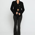 Women wearing black denim trucker jacket with hand on hip - button front cotton jacket styled with high waist flare jeans