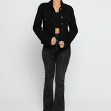 Women wearing black denim trucker jacket with hand on hip - button front cotton jacket styled with high waist flare jeans