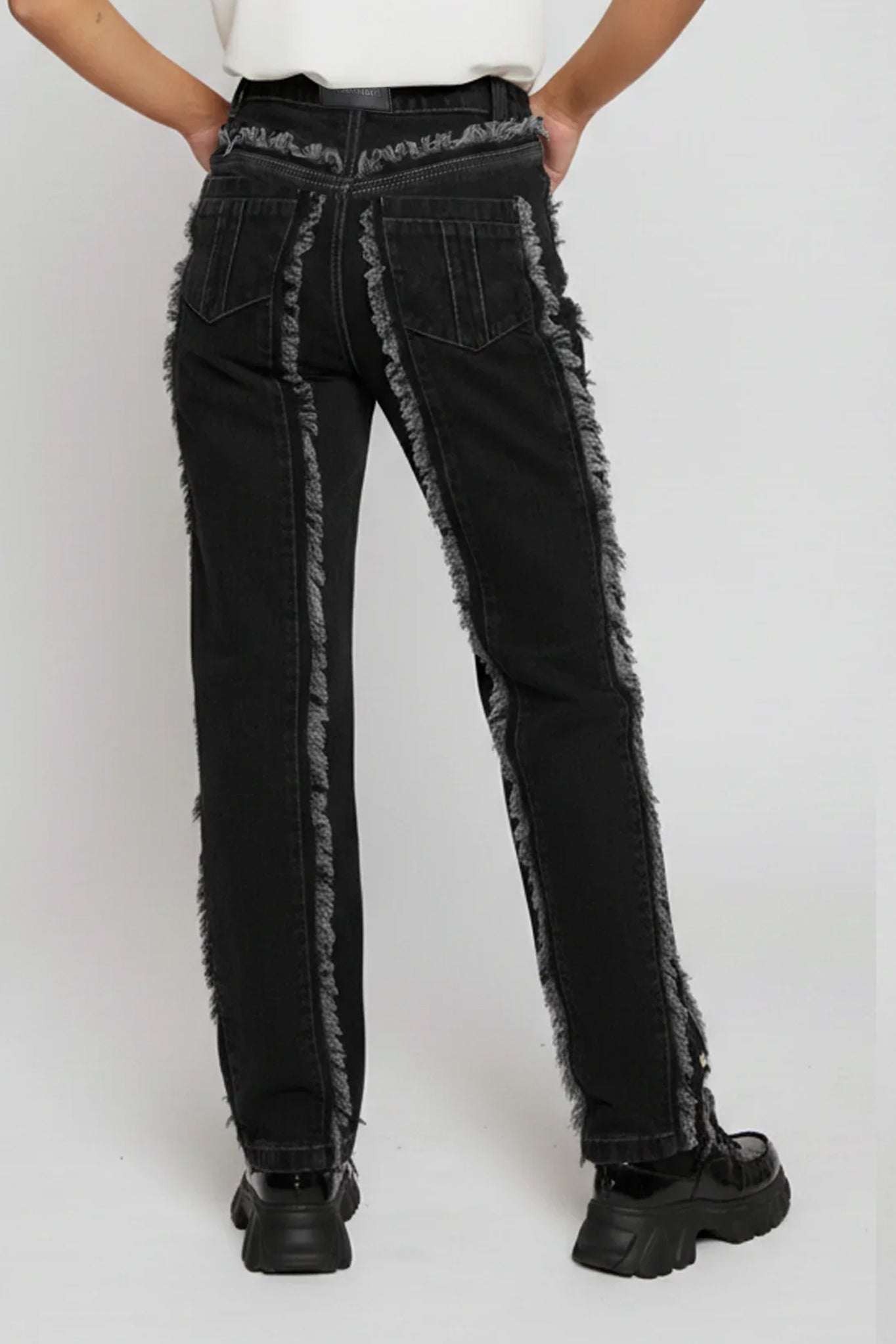 Person wearing black distressed jeans with gray trim on a white background