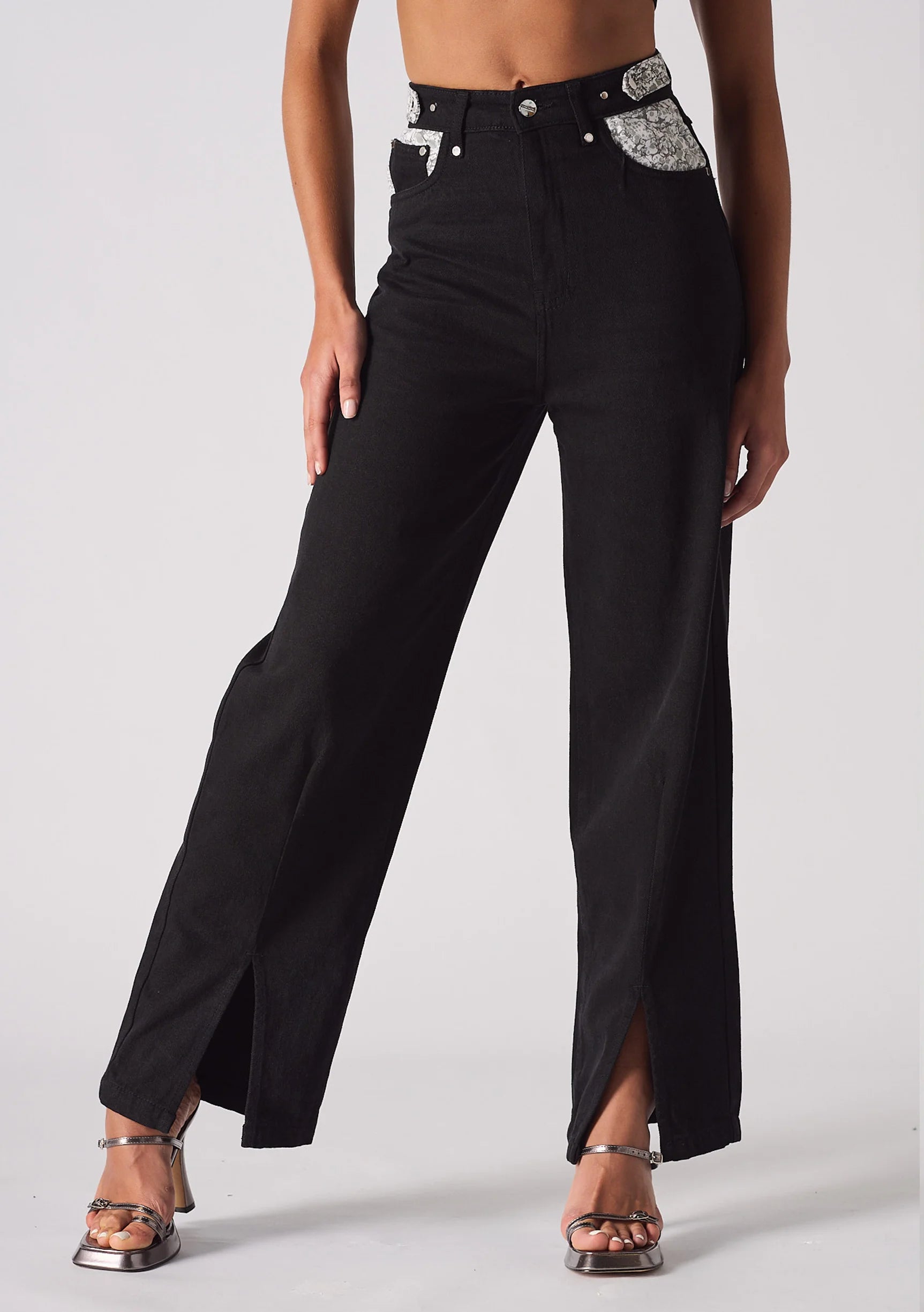 Studio shot of model wearing black wide leg jeans with embellished pockets